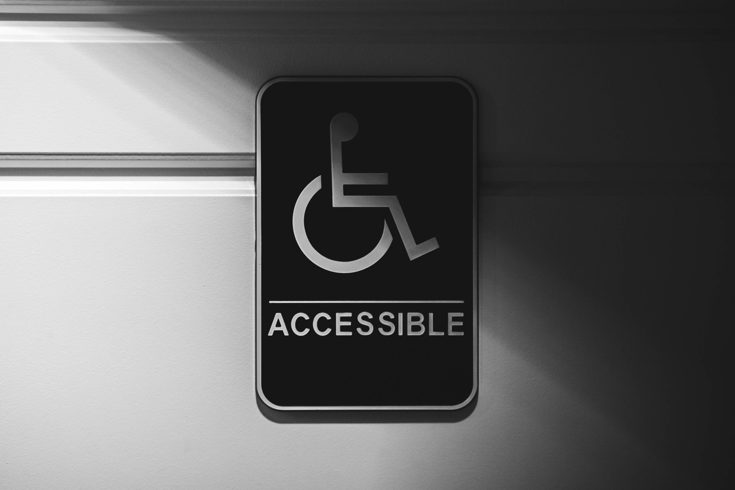 Accessibility sign showing the International Symbol of Access - a wheelchair icon above the word ACCESSIBLE - mounted on a wall