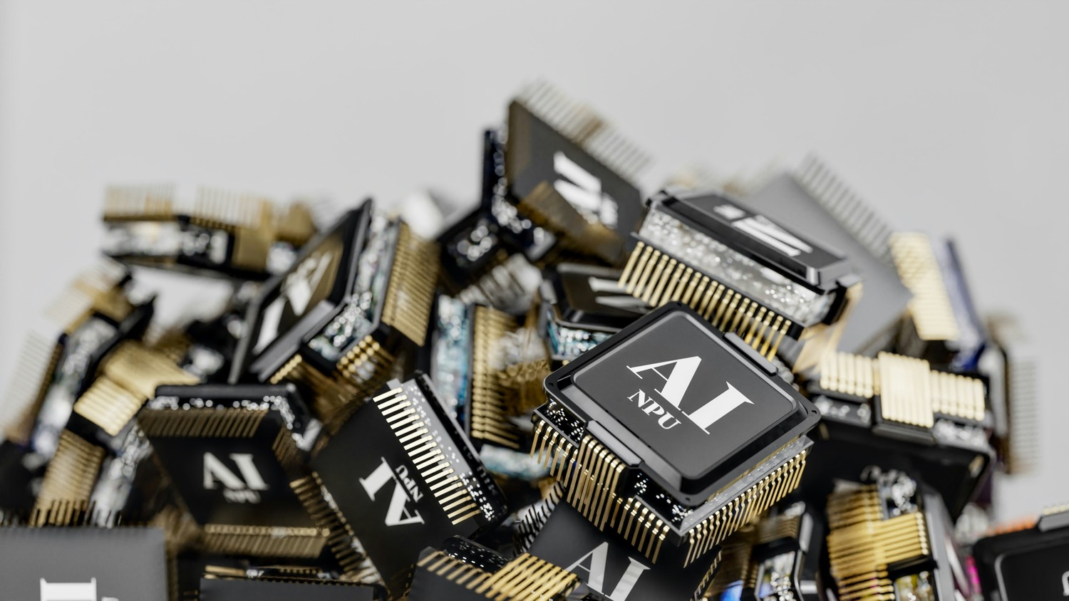 A pile of black AI NPU processor chips with gold pins, one chip in focus in the foreground